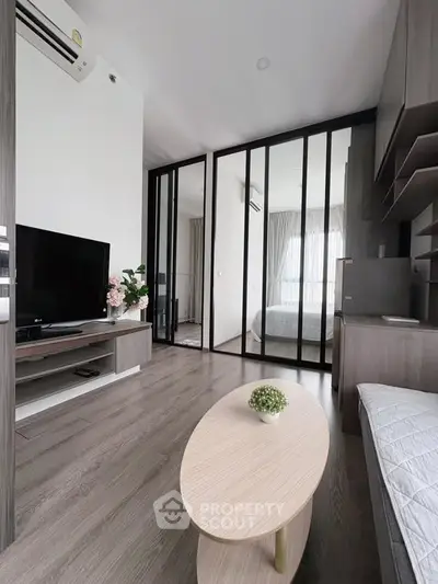 Modern living room with sleek design and mirrored sliding doors leading to a bedroom.