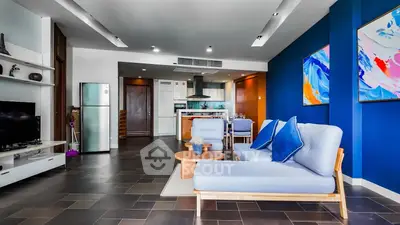 Modern living room with open kitchen, stylish decor, and vibrant blue accents