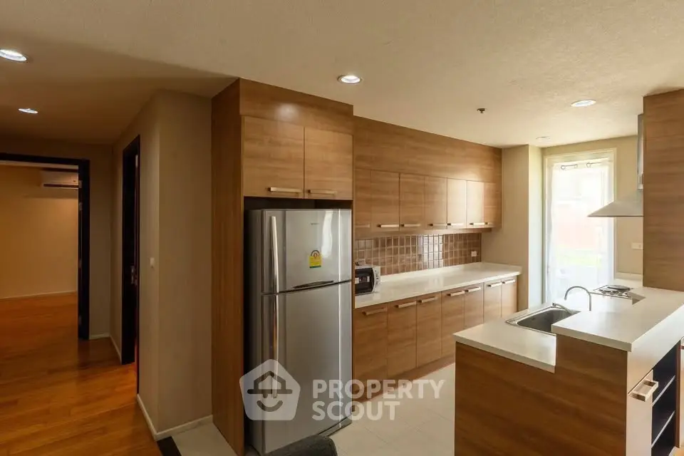 Modern kitchen with wooden cabinets and stainless steel appliances in a stylish apartment.