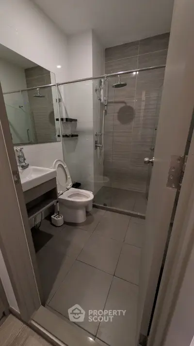 Modern bathroom with glass shower and sleek fixtures in contemporary apartment.