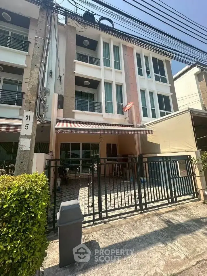 Charming three-story townhouse with gated entrance and modern facade in a sunny neighborhood.