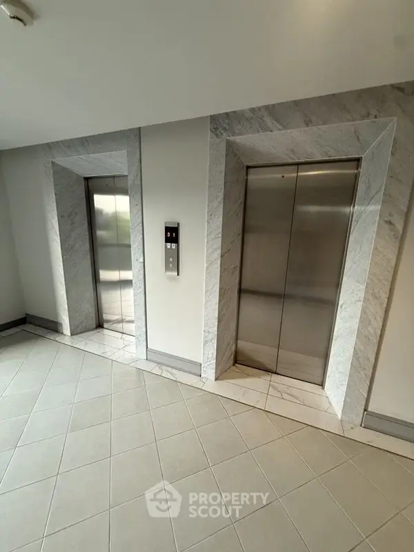 Modern building elevator lobby with sleek marble accents and tiled flooring.
