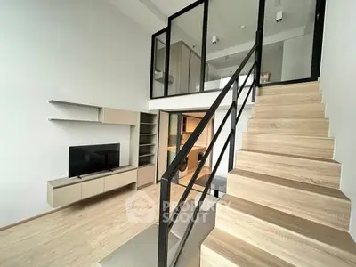 Modern loft-style living room with sleek staircase and minimalist design.