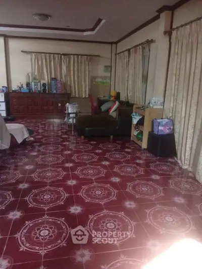 Spacious living room with patterned red tile flooring and elegant curtains, perfect for family gatherings.