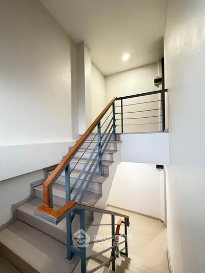 Modern staircase with sleek metal railing in a bright, minimalist building interior.