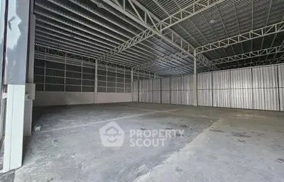 Spacious industrial warehouse with high ceilings and metal framework, ideal for storage or manufacturing.