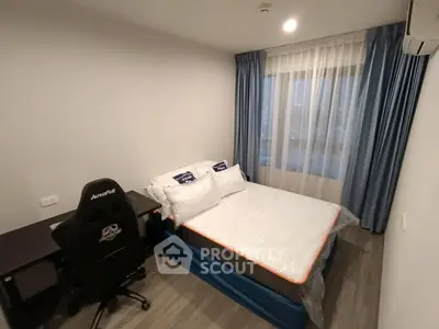 Modern bedroom with desk and gaming chair, featuring blue curtains and a large window.