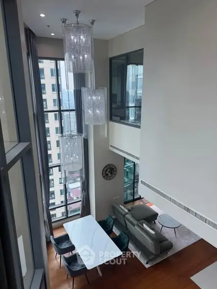 Luxurious high-ceiling living room with modern decor and large windows offering city views.