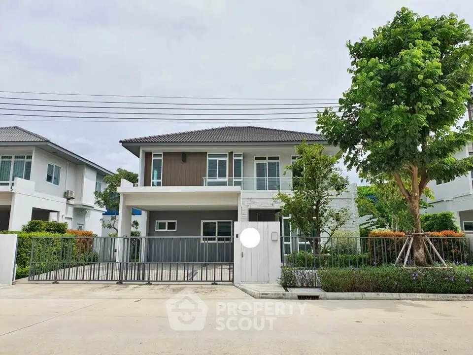 Modern two-story house with landscaped garden and gated entrance in a serene neighborhood.