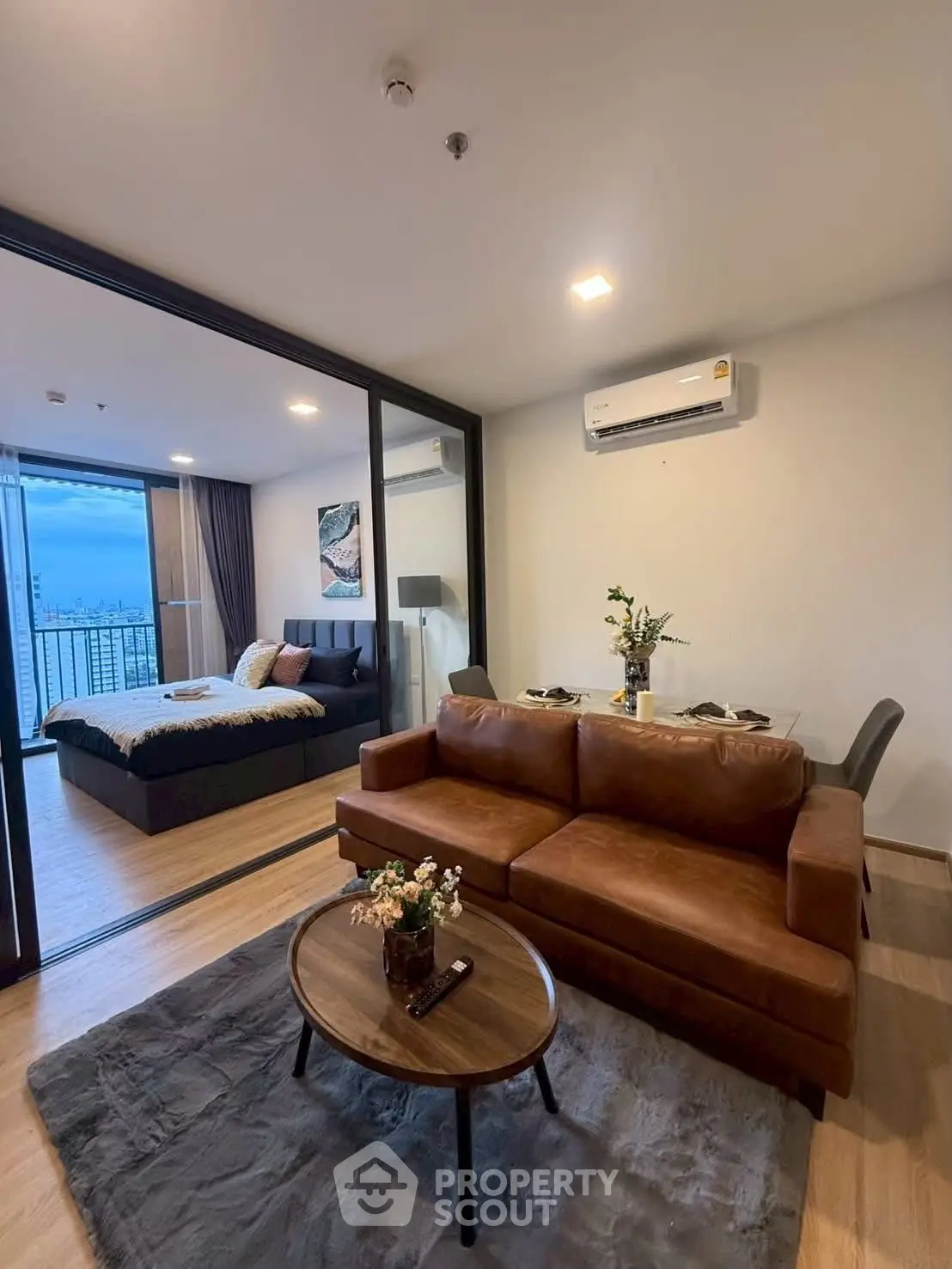 Modern open-plan living room with cozy brown sofa and elegant bedroom view.