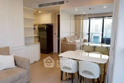 Modern living room with dining area and city view, featuring elegant furniture and mirrored wall.
