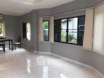 Spacious living room with large windows and natural light, perfect for family gatherings.