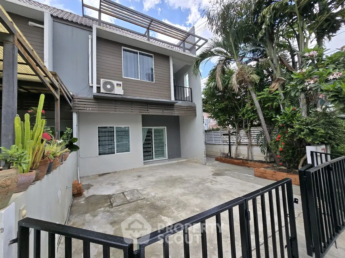Charming townhouse exterior with gated driveway and lush garden