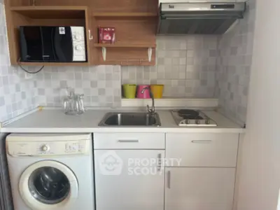 Compact kitchen with washing machine and gas stove in modern apartment