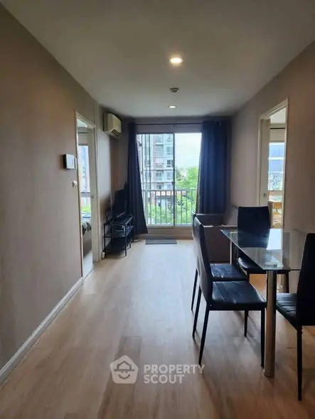 Modern dining area with glass table and chairs, featuring a balcony view in a stylish apartment.