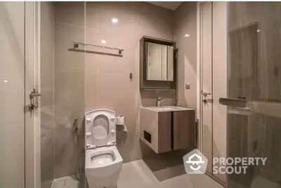 Modern bathroom with sleek glass shower enclosure, wooden vanity, and well-placed lighting creating a warm, inviting space.