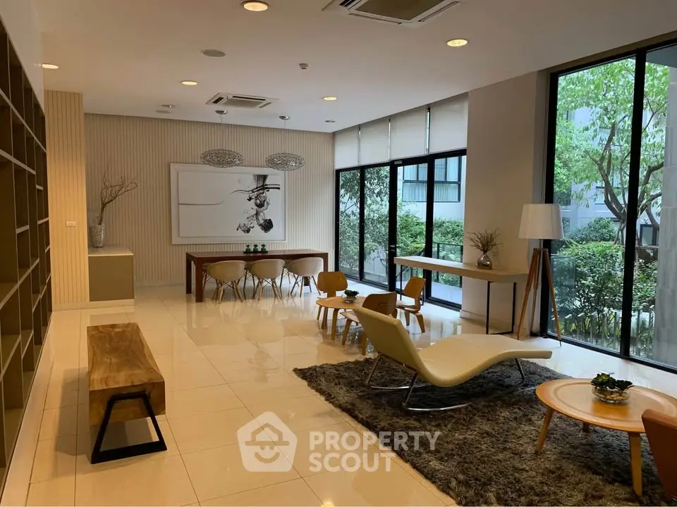 Modern living room with stylish furniture and large windows overlooking greenery.