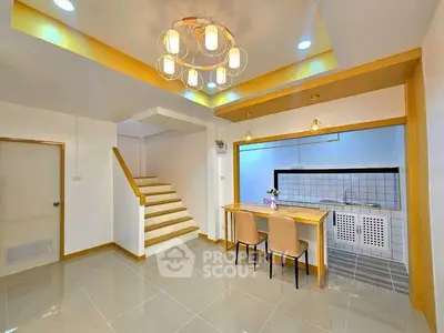 Modern open-plan kitchen and dining area with stylish lighting and staircase.