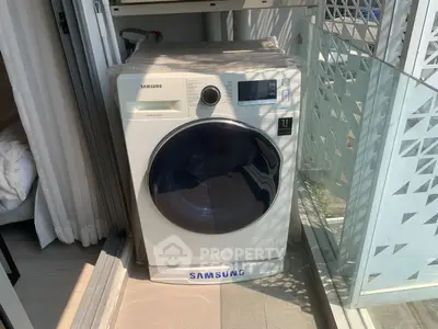 Modern Samsung washing machine on a balcony with stylish glass railing.