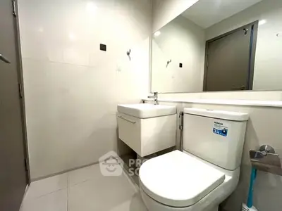 Modern bathroom with sleek fixtures and large mirror in a contemporary home.