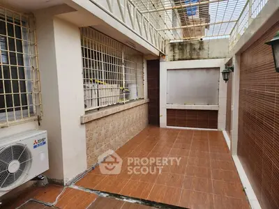 Spacious tiled balcony with secure metal grilles and air conditioning unit.