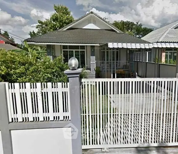 Charming single-story house with a spacious front yard and gated entrance, perfect for family living.