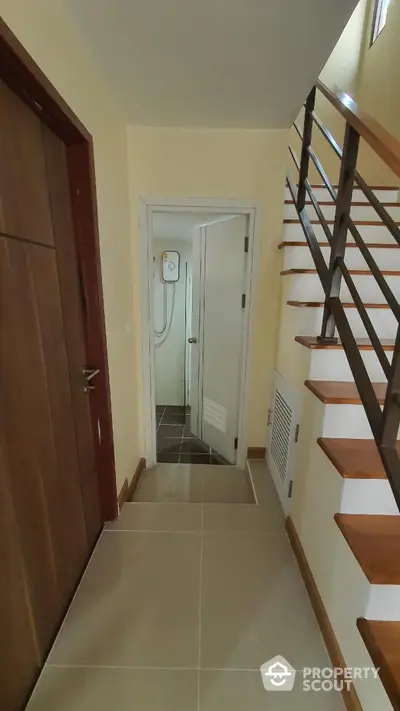 Compact hallway with staircase and bathroom door, featuring modern design and neutral tones.