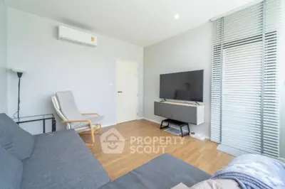Modern living room with sleek furniture and natural light, featuring a wall-mounted TV and air conditioning.