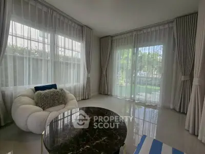 Spacious living room with elegant curtains and modern furniture, offering a serene garden view.