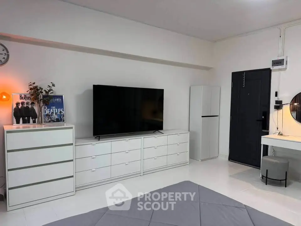 Modern bedroom with sleek white furniture and large TV