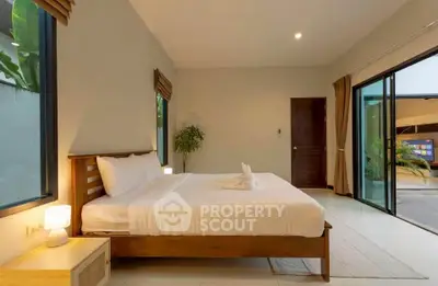Spacious bedroom with modern decor and large windows offering garden views.