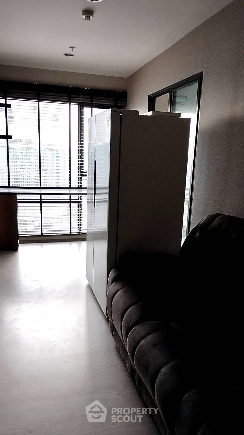 Modern apartment interior with large windows and sleek refrigerator, offering a stylish urban living space.