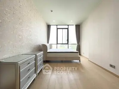 Spacious bedroom with elegant decor and large window offering natural light and city views.