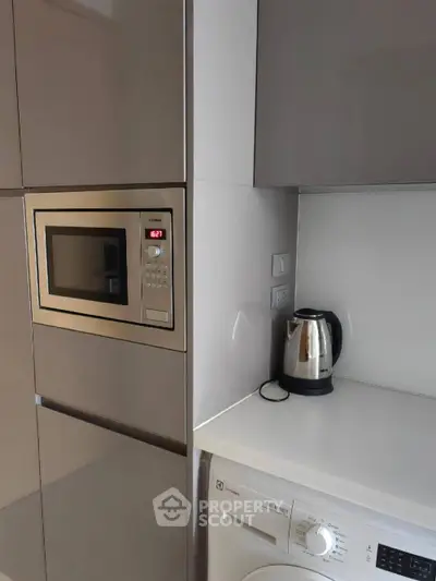 Modern kitchen with built-in microwave, kettle, and washing machine in sleek cabinetry.