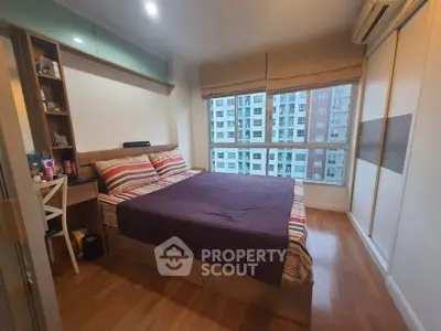 Spacious bedroom with large window offering city view, featuring cozy bed and modern decor.