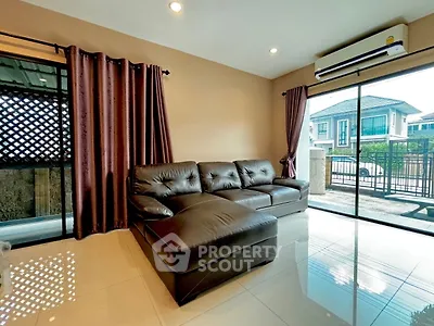 Spacious living room with modern leather sofa and large windows offering natural light.