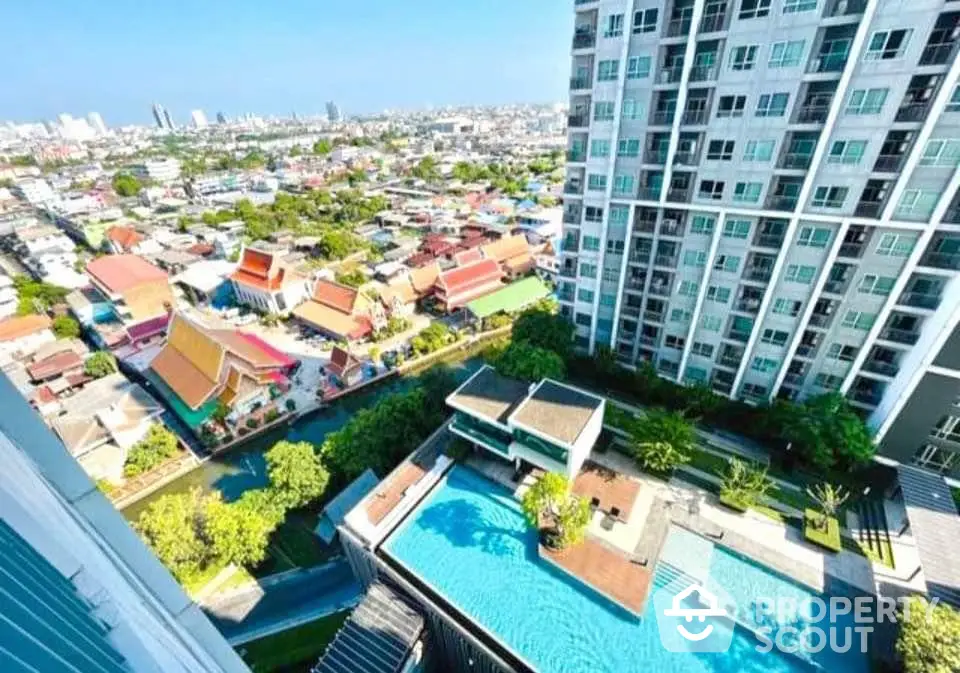 Stunning city view from high-rise apartment with pool and lush greenery.