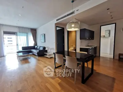 Spacious open-plan living room with modern kitchen and dining area, featuring hardwood floors and natural light.