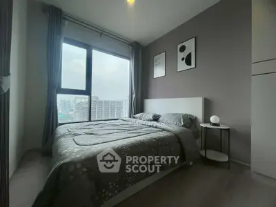 Modern bedroom with large window offering city view, stylish decor, and cozy bedding.