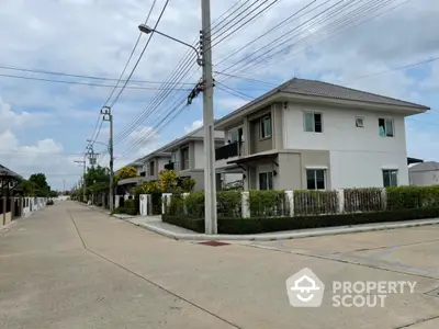 Modern suburban townhouse with clean lines and lush greenery on a quiet street.