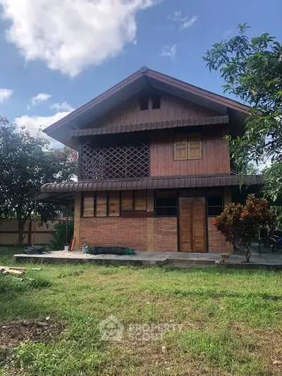 Charming rustic wooden house with lush garden and clear blue sky.