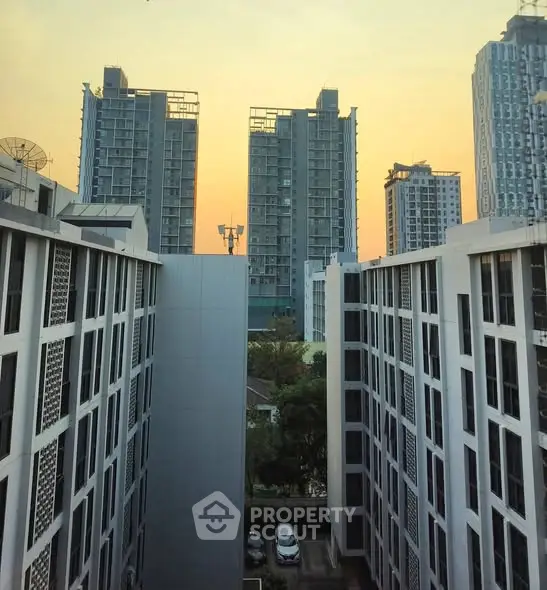 Stunning urban view from a modern apartment balcony at sunset, showcasing high-rise buildings.