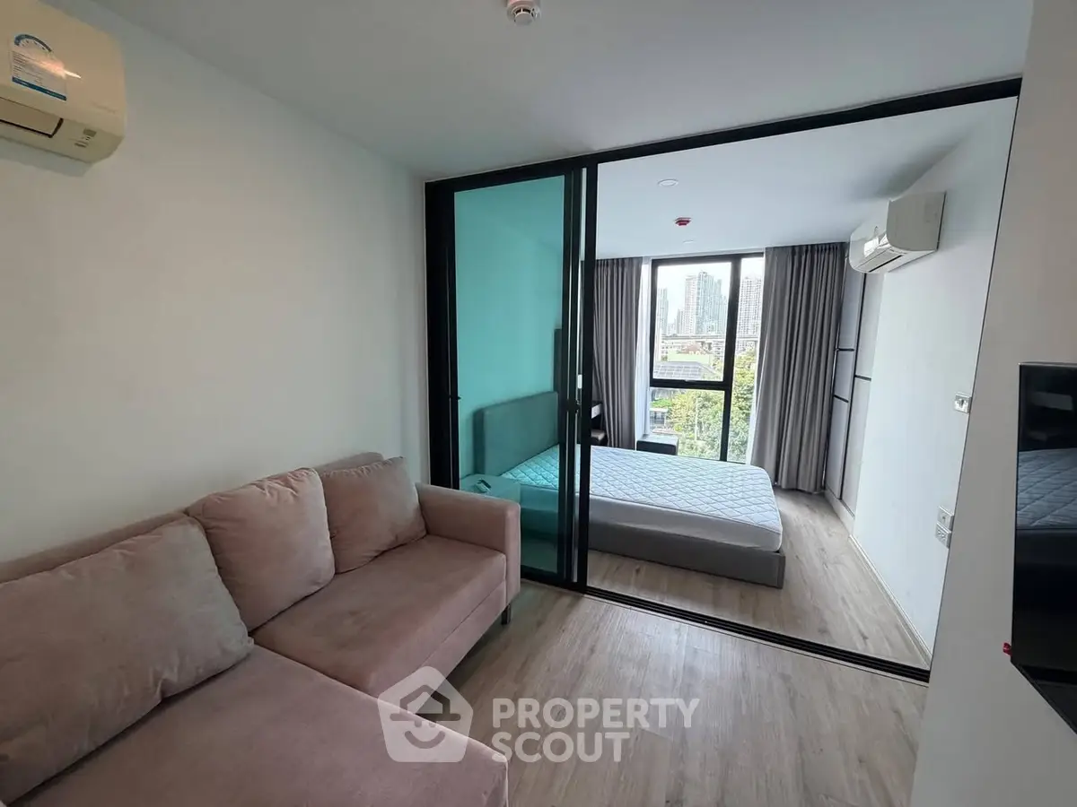 Modern apartment with cozy living room and bedroom, featuring large windows and stylish decor.