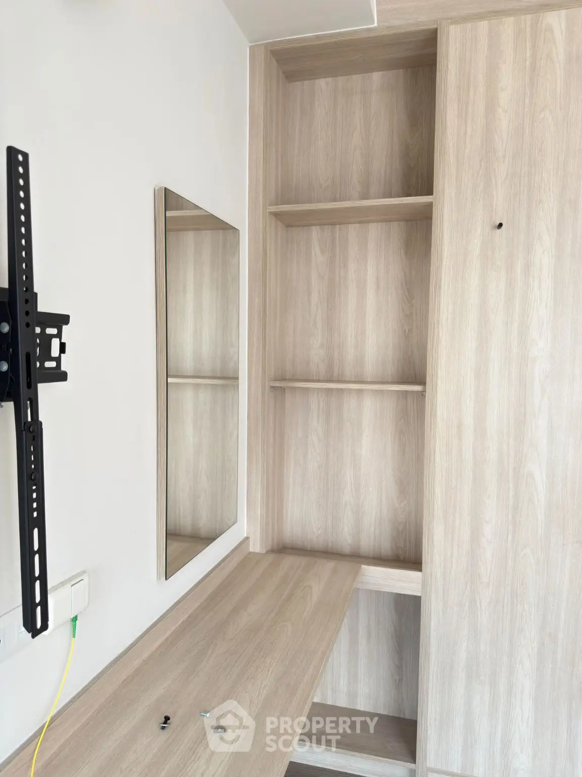 Modern wooden storage unit with built-in desk and TV mount in a stylish room.
