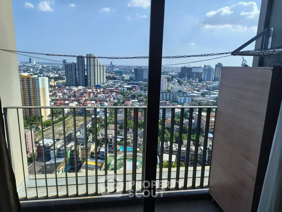 Stunning cityscape view from a high-rise balcony with clear skies and urban skyline.