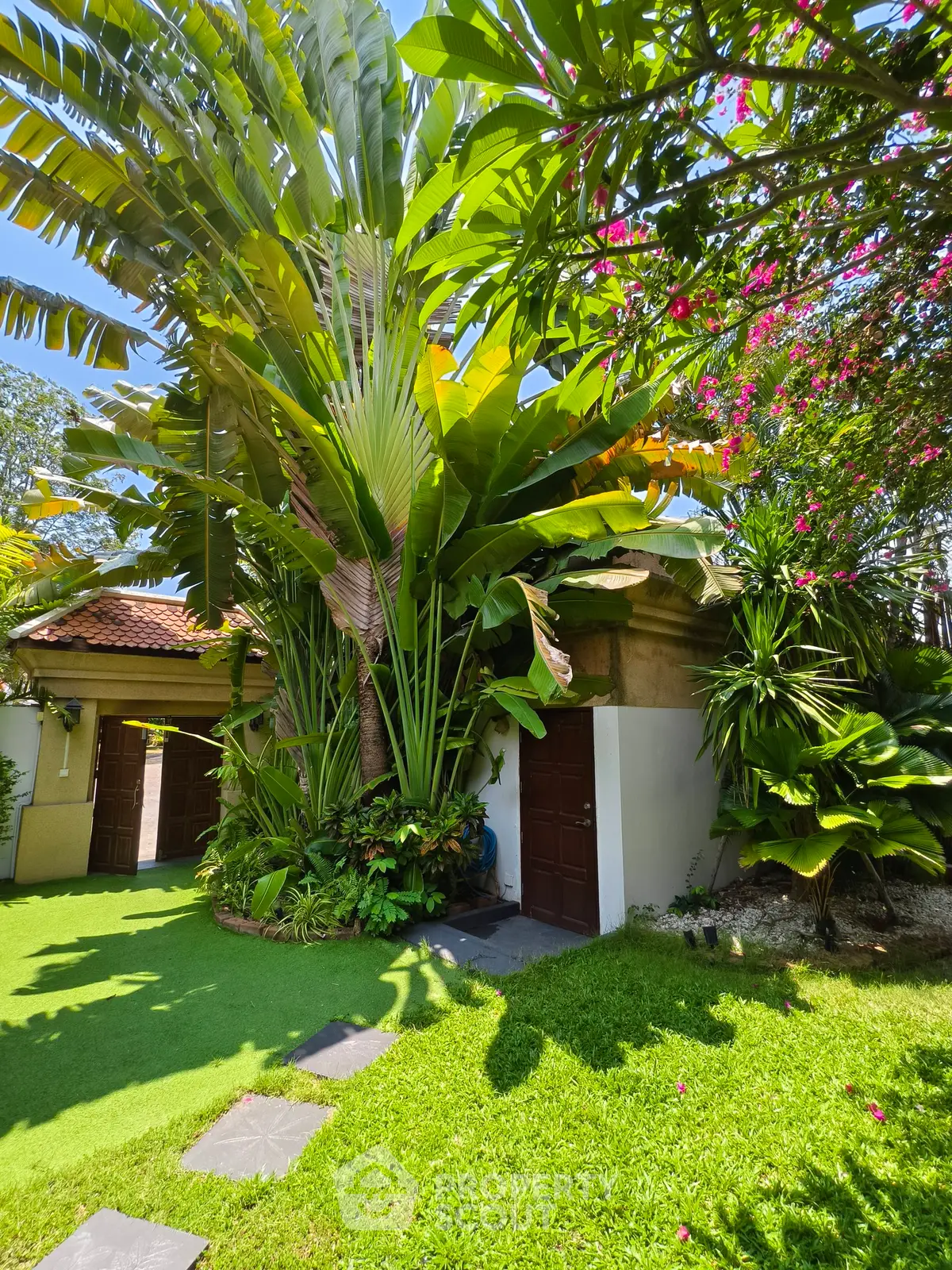 Tropical garden with lush greenery and charming exterior of a villa, perfect for serene living.