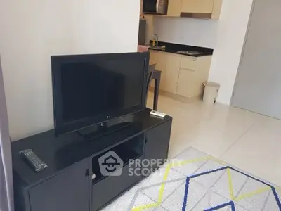 Modern living room with sleek TV stand and compact kitchen area in open layout apartment.
