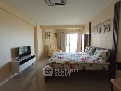 Spacious bedroom with modern decor and natural light, featuring a cozy seating area and stylish TV stand.