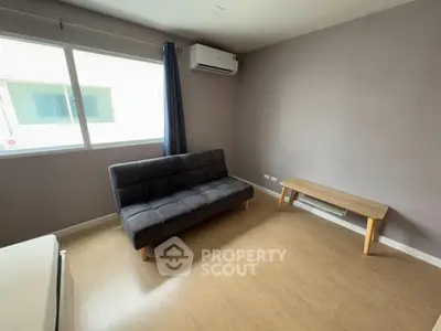 Cozy living room with modern sofa and natural light from large window.