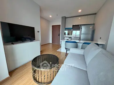 Modern living room with open kitchen, featuring sleek furniture and contemporary design.